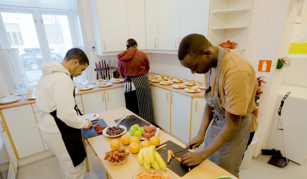 Tre gutter jobber med å forberede mat på skolekjøkkenet